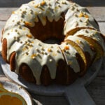 olive oil and orange bundt cake, partially sliced with an orange glaze on top